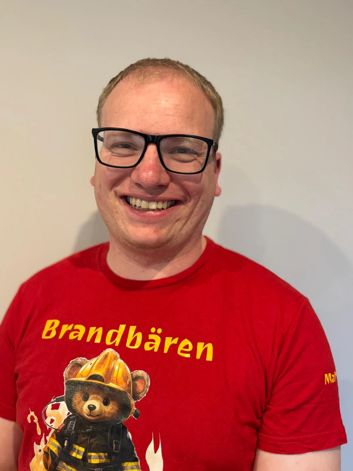 Matthias Petersen lächelt in einem roten Brandbären-Shirt