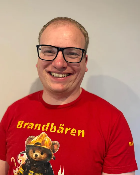 Matthias Petersen lächelt in einem roten Brandbären-Shirt